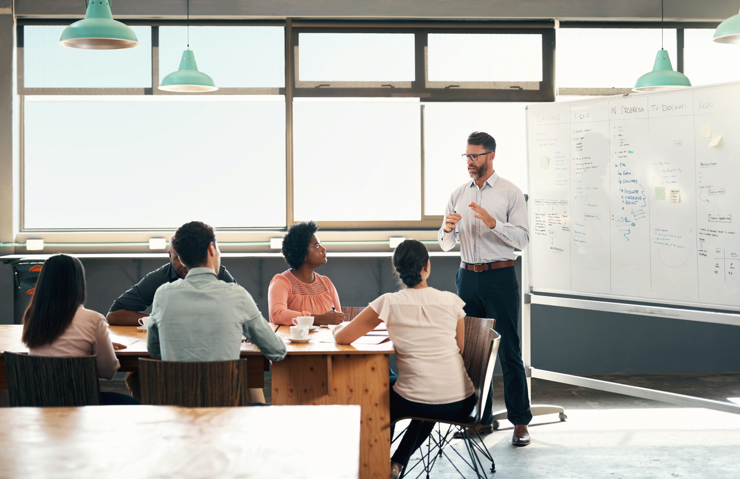 Planning, strategy and a whiteboard presentation by a businessman coaching on financial growth in a meeting. Seo leader training team with marketing ideas to staff in training in a conference room